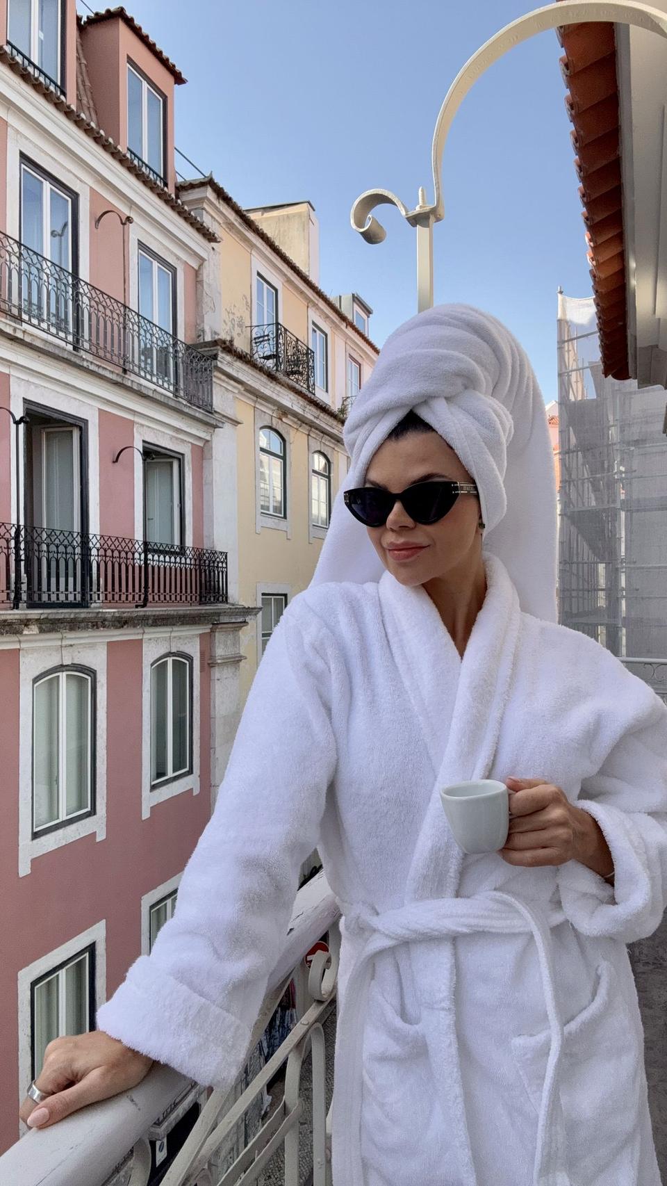 Juliana in a robe with an espresso on a Lisbon balcony