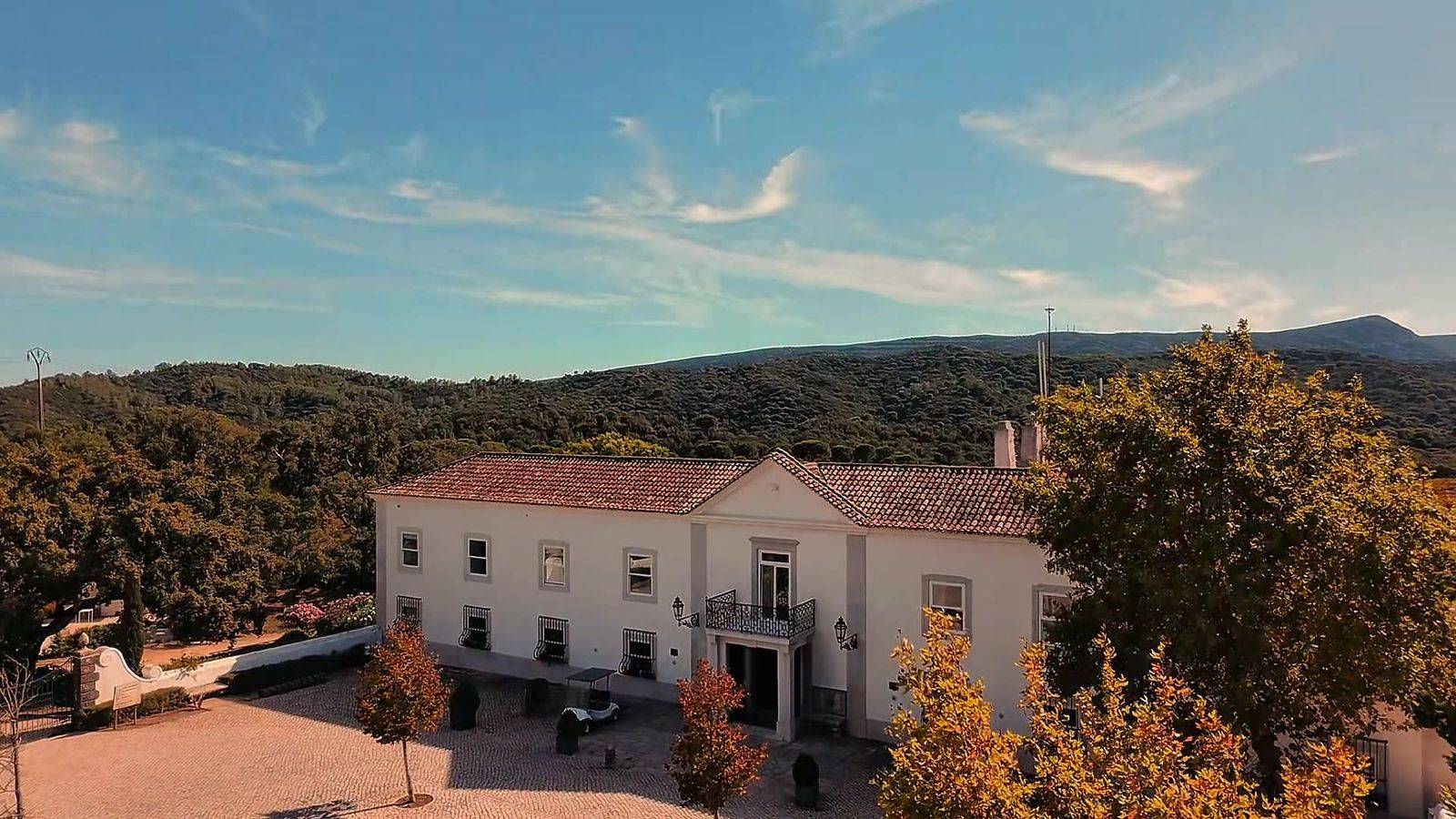 Aerial view of Hotel Casa Palmela among autumn trees and the Arrábida hills